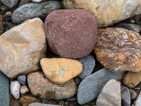 Ansammlung von Steinen in Rot-, Gelb-, Braun- und Grautönen mit weißen Anteilen